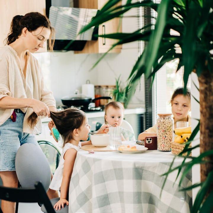 Mother helping children with breakfast in the kitchen.