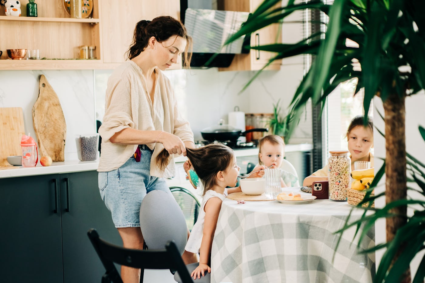 Mother helping children with breakfast in the kitchen.