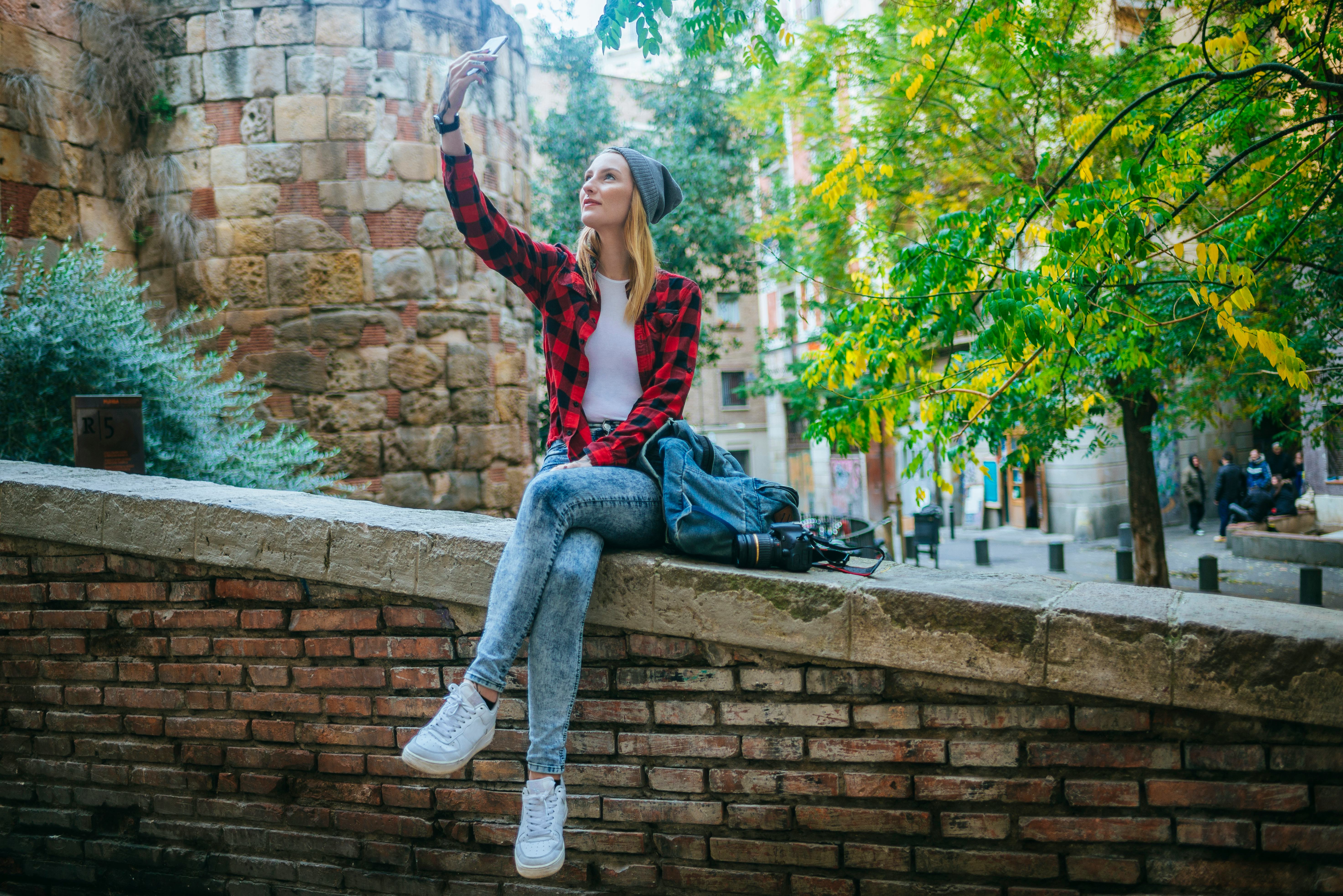 Young woman taking a selfie with a smart phone, sitting on the outside.