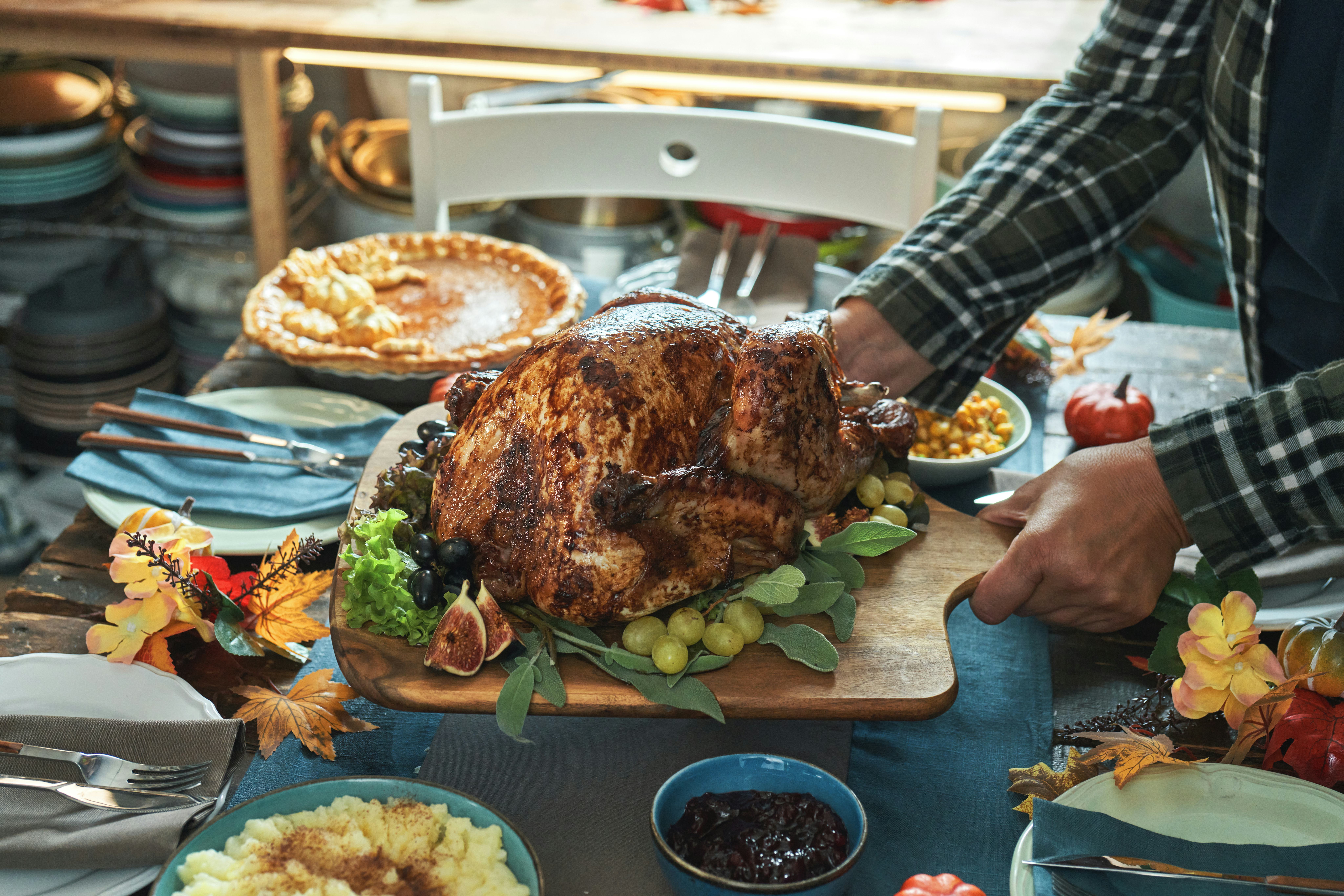 Having Stuffed Turkey for Thanksgiving Holiday Dinner with Vegetables, Pumpkin Pie and Side Dishes