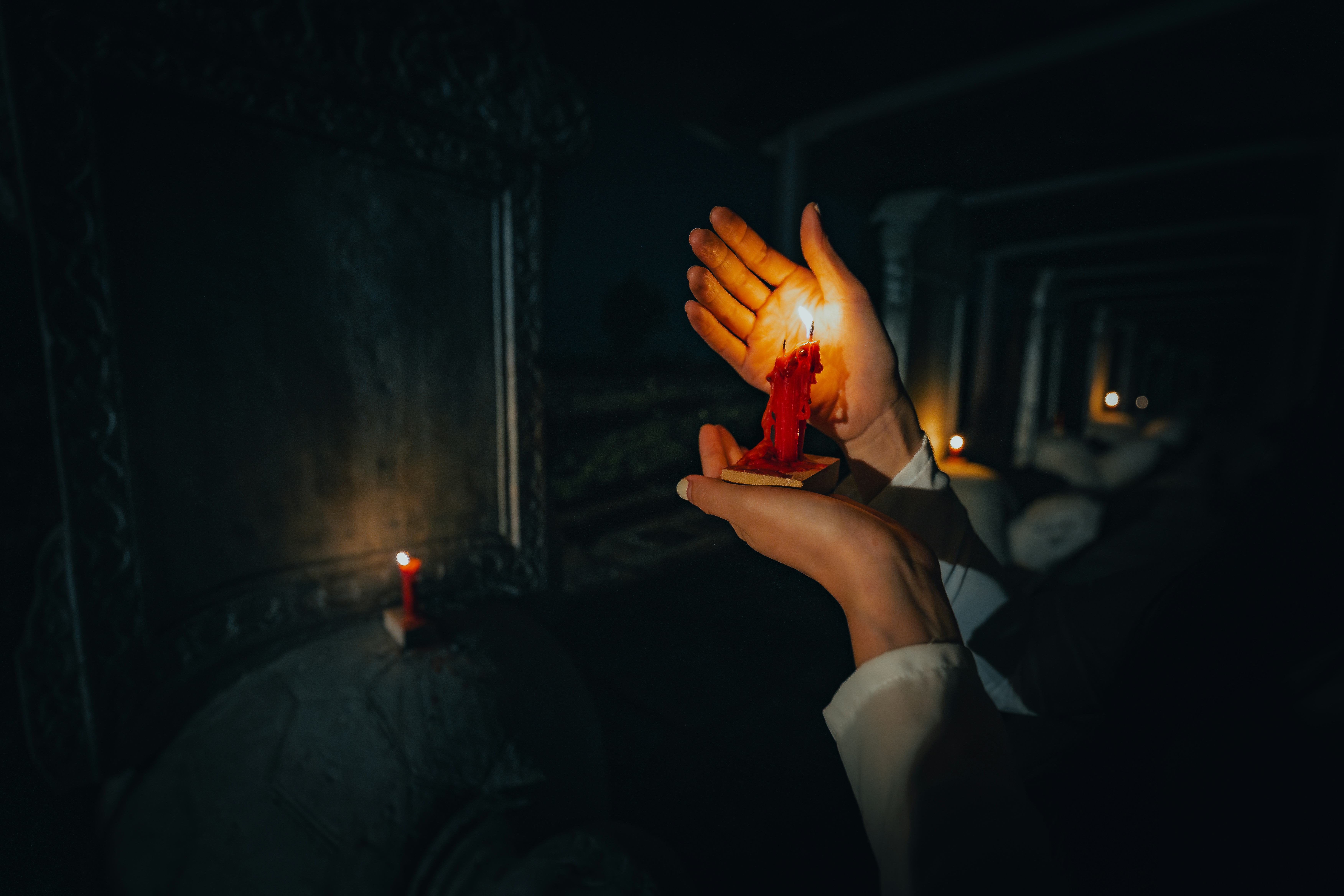 A Vietnamese girl in a traditional ao dai is praying in a temple surrounded by many bright candles. ...