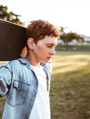 sad kid with the skateboard on the shoulder