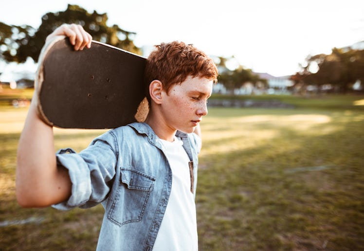 sad kid with the skateboard on the shoulder