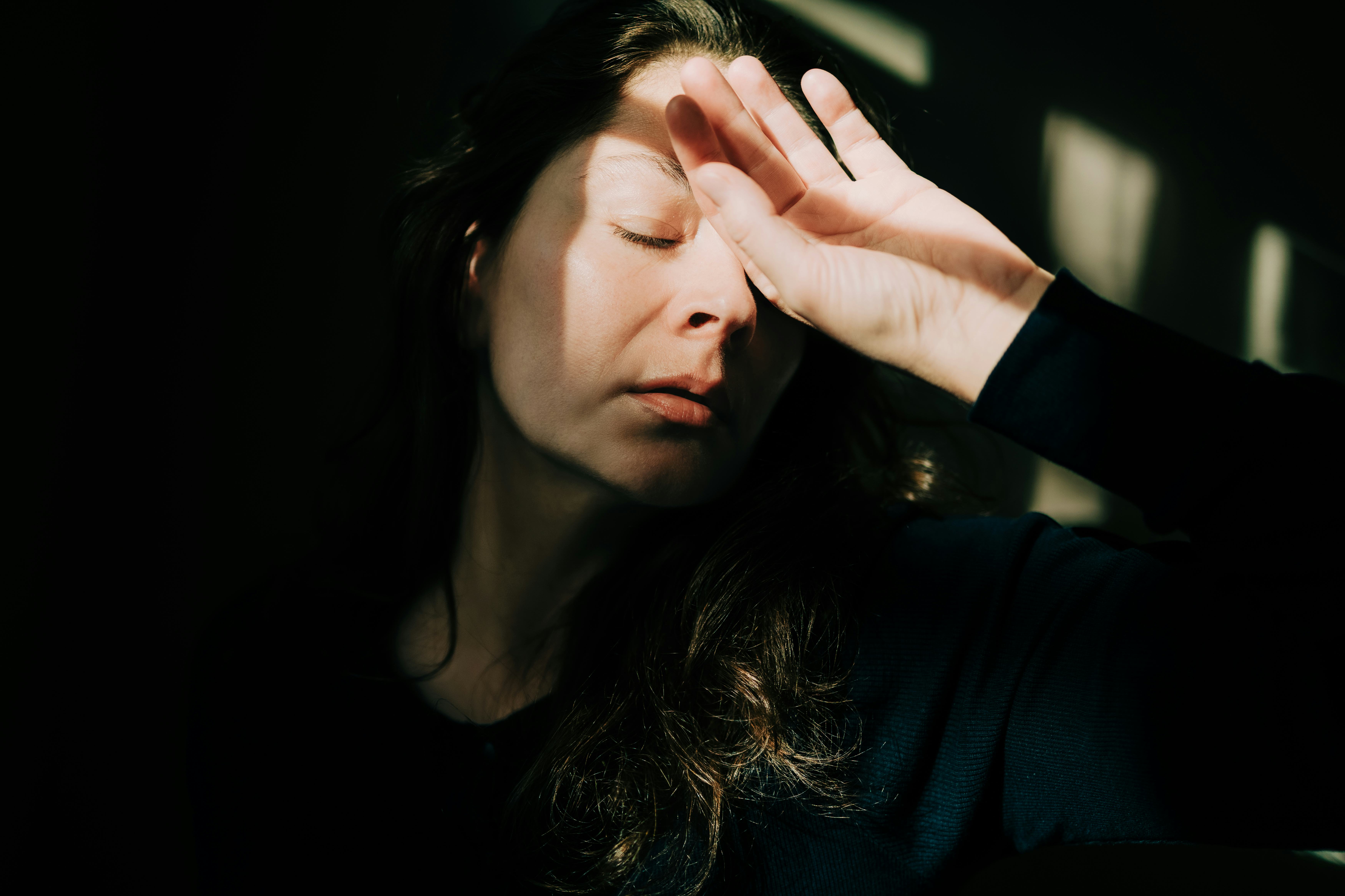 Woman covering eyes with hand experiencing headache and exhaustion