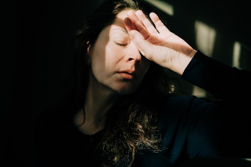 Woman covering eyes with hand experiencing headache and exhaustion