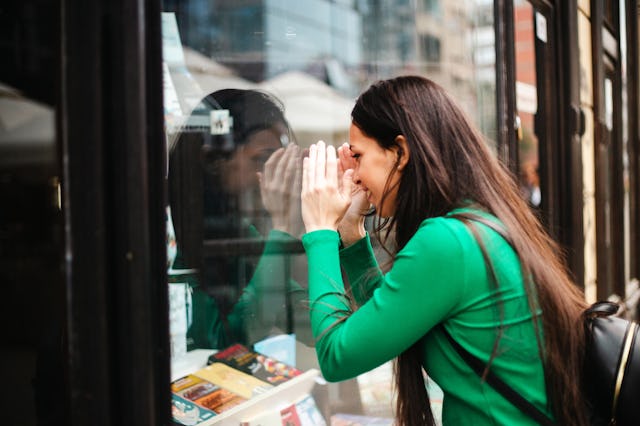 A woman looking into the window of a book store.