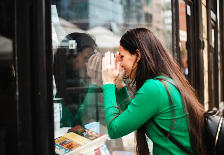 A woman looking into the window of a book store.