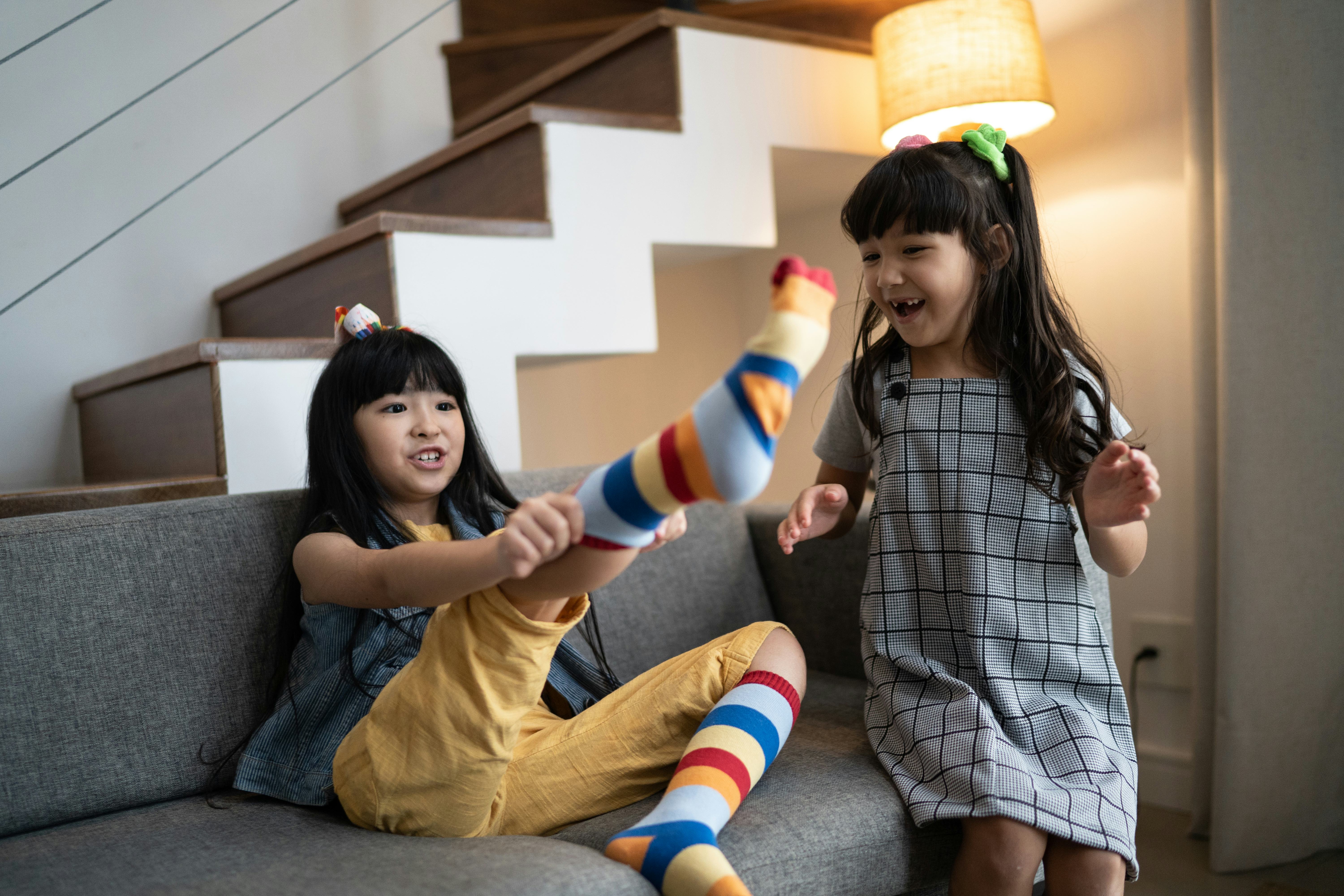Happy sisters putting on colorful socks at home