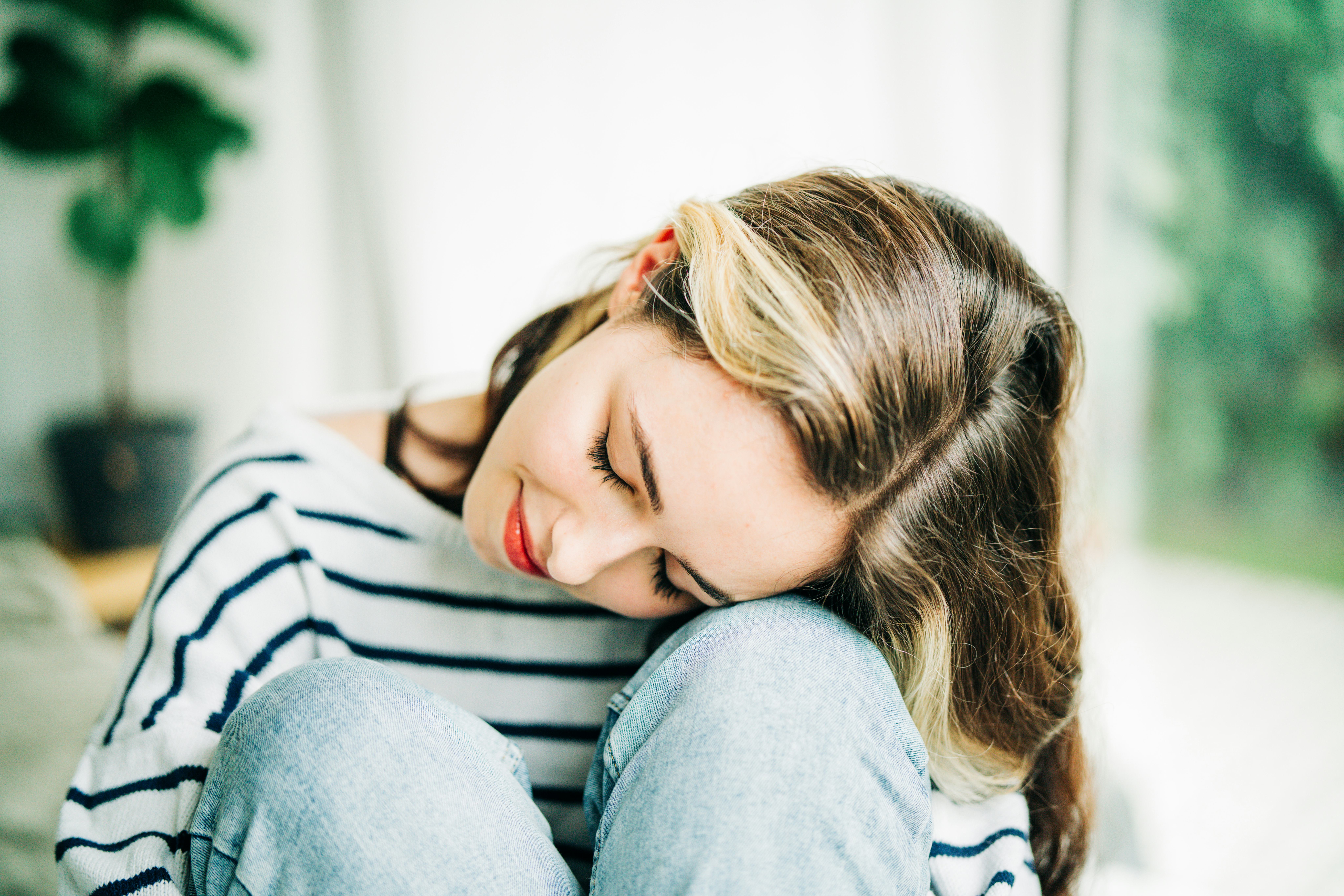 A sad teenage girl sitting on the sofa.