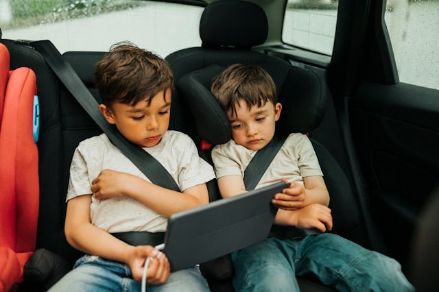 Two boys watch an iPad in the back of a car.