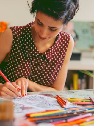 Young smiling woman coloring book for adults in her office or apartment, Enjoy coffee break while co...