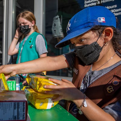 Madar Mee, 10, left, and Emma Diaz, 7, right, are selling Girl Scout Cookies in the Mar Vista neighborhood at on Friday, Feb. 11, 2022 in Los Angeles, CA. Some customers were buying several boxes of cookie.