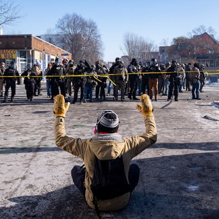 MINNEAPOLIS, MN. - JANUARY 2026: A protester sits on the street with his arms up in front of a gaggl...