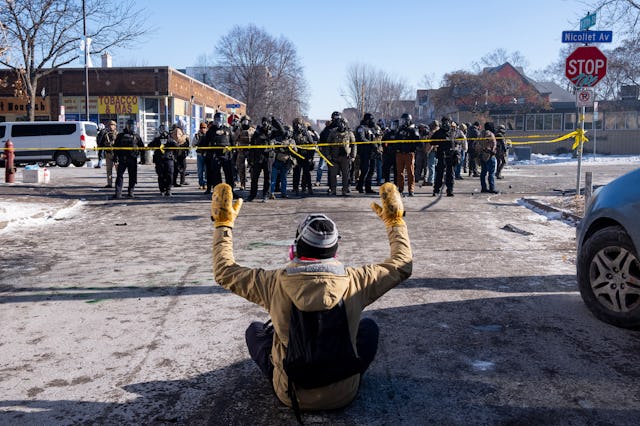 MINNEAPOLIS, MN. - JANUARY 2026: A protester sits on the street with his arms up in front of a gaggl...