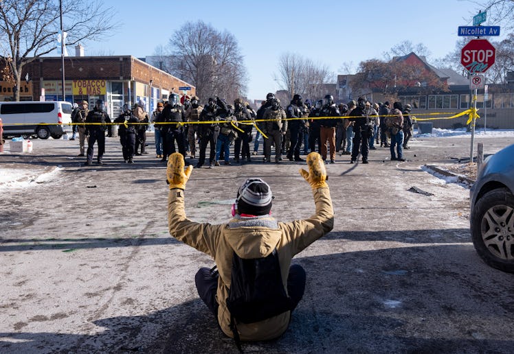 MINNEAPOLIS, MN. - JANUARY 2026: A protester sits on the street with his arms up in front of a gaggl...