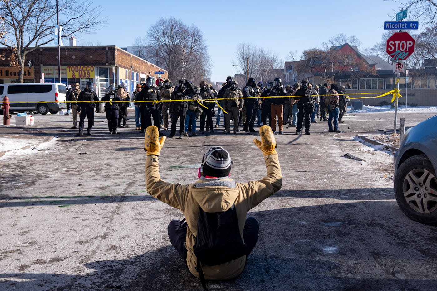 MINNEAPOLIS, MN. - JANUARY 2026: A protester sits on the street with his arms up in front of a gaggle of federal agents and Minneapolis Police on W. 27th St and Nicollet Avenue in south Minneapolis after Alex Pretti was fatally shot by federal agents in the area early Saturday morning, January 24, 2026. (Photo by Richard Tsong-Taatarii/The Minnesota Star Tribune)