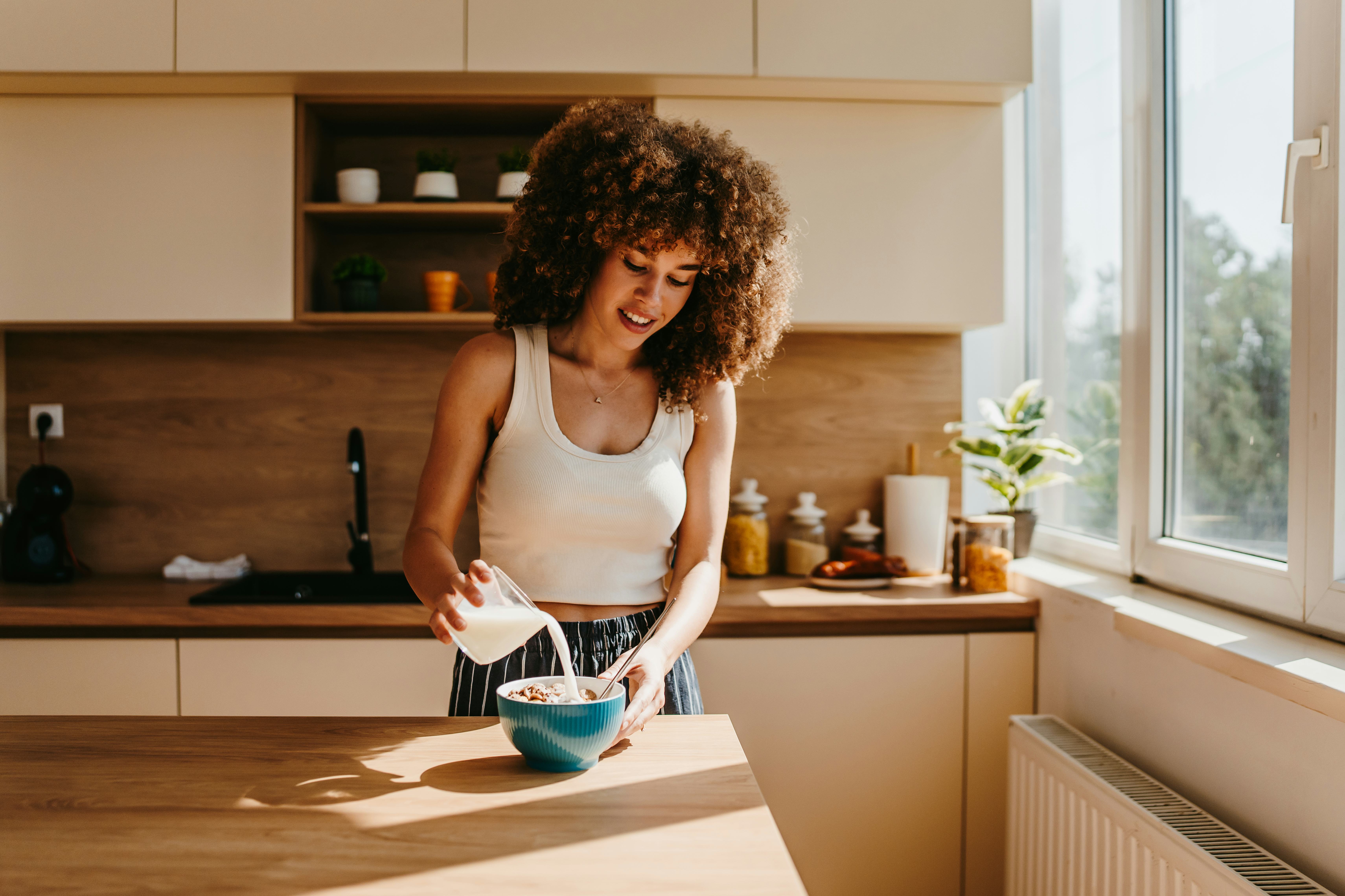 Happy young woman preparing a healthy breakfast in a modern kitchen