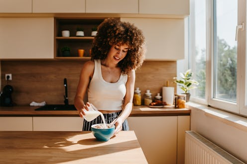 Happy young woman preparing a healthy breakfast in a modern kitchen