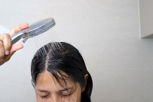 A woman is taking a shower and washing her hair in the bathroom.