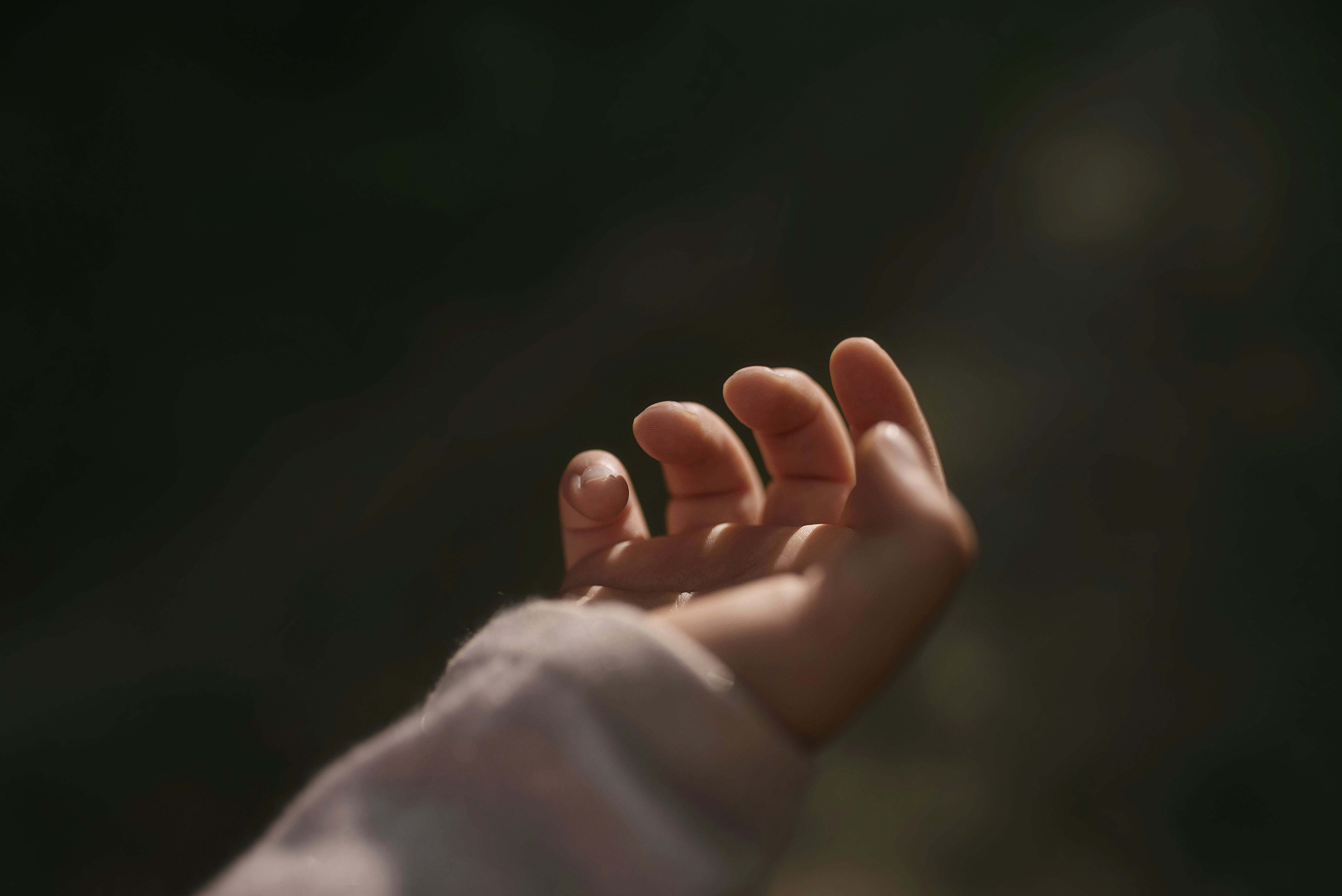 Tender little hand of child in dark key. Fingers close-up. Woman's happiness. Symbolic hand helping ...
