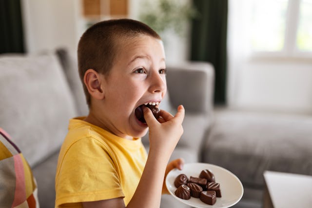 A little boy eating chocolate cakes at home.