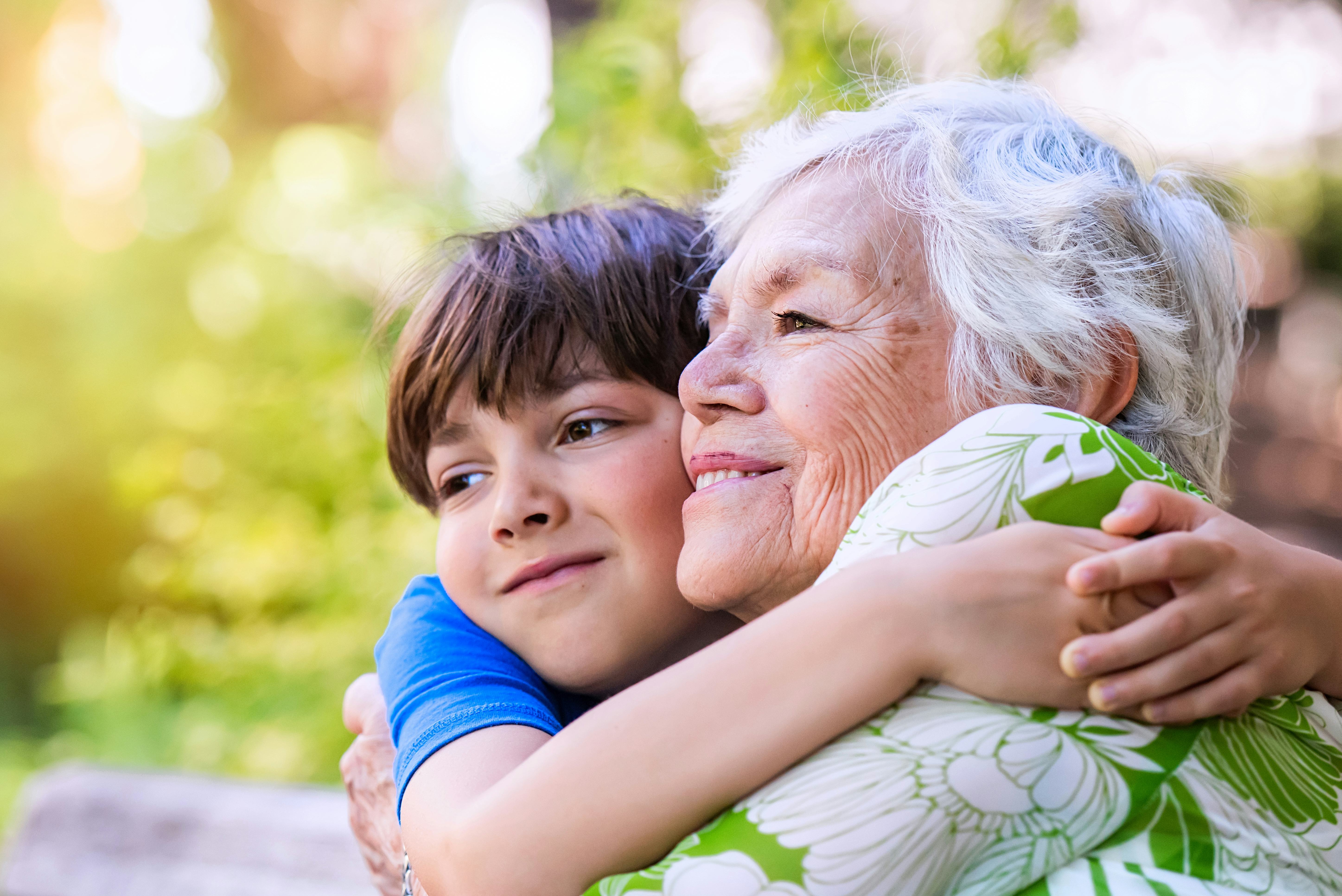 A happy boy hugging his grandmother. 