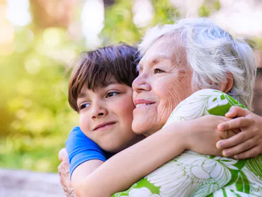 A happy boy hugging his grandmother.