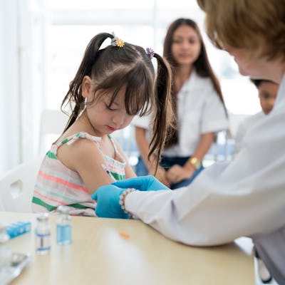 A small child receives a vaccination from a medical professional.