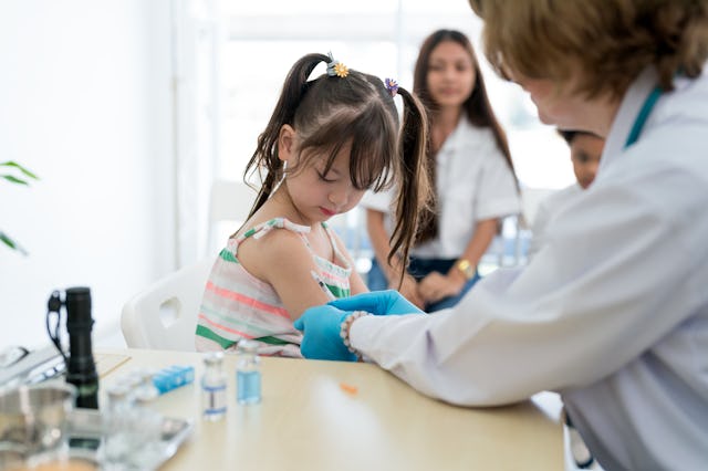 A small child receives a vaccination from a medical professional.