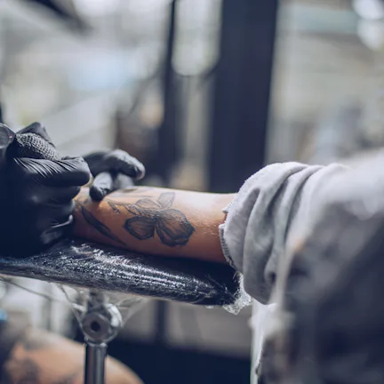 Artist making tattoo on customer's hand in studio