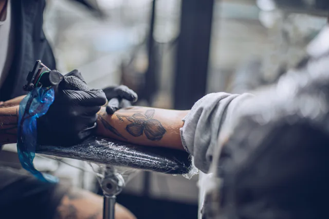 Artist making tattoo on customer's hand in studio