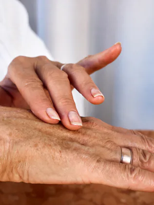 Elderly hands with age spots and wrinkles applying moisturizing cream, close-up of daily skincare ro...
