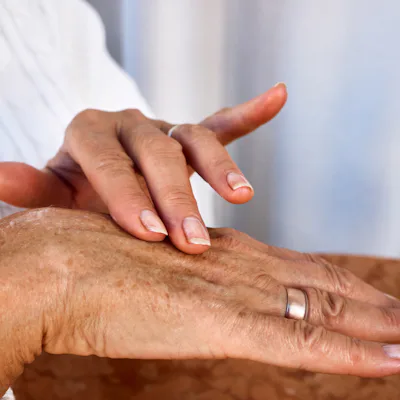 Elderly hands with age spots and wrinkles applying moisturizing cream, close-up of daily skincare routine illustrating aging, self-care, dermatology and gentle hand treatment