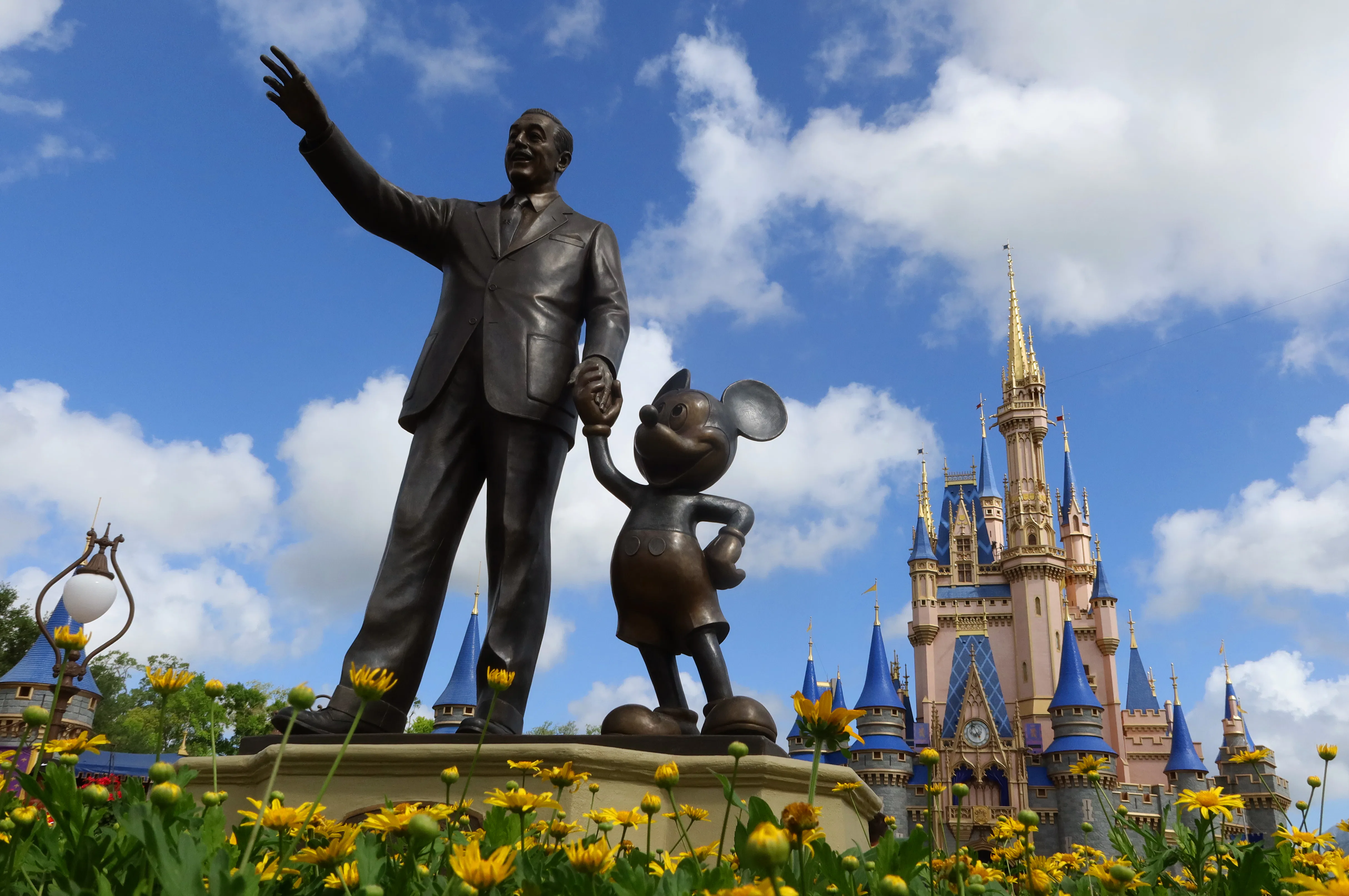 ORLANDO, FL - APRIL 3: A statue of Walt Disney and Mickey Mouse stands in a garden in front of Cinde...