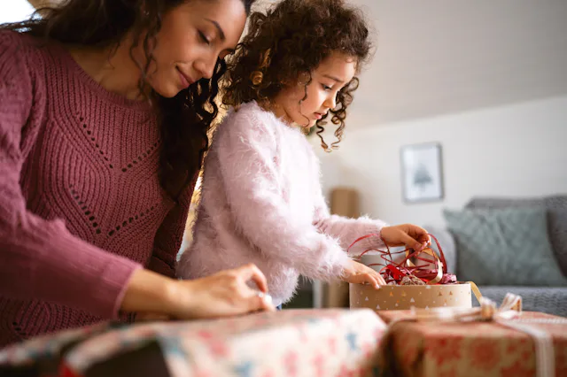 Caucasian mother and daughter together, wrapping and decorating Christmas presents