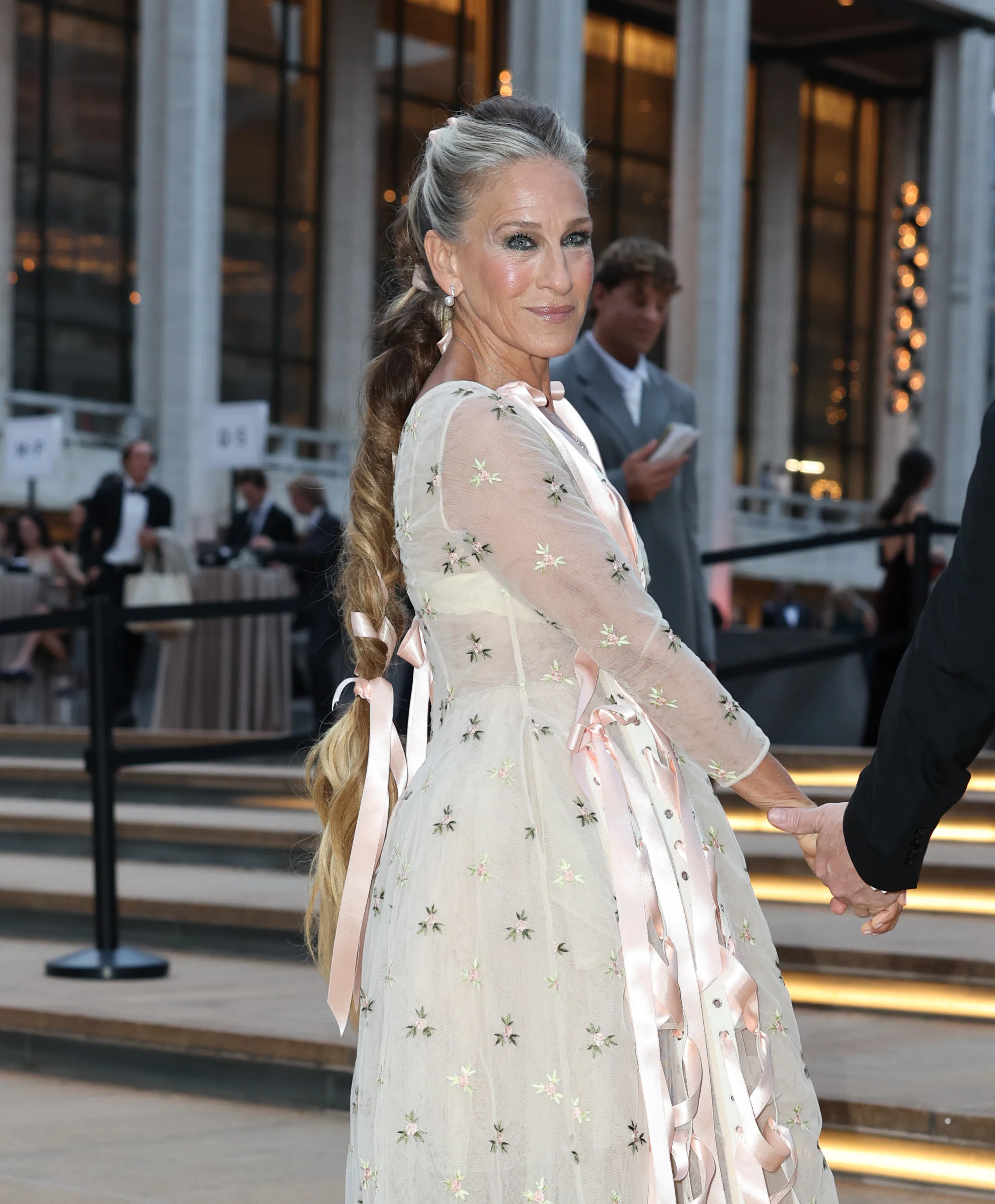 Sarah Jessica Parker at Lincoln Center, standing on the steps with a long braided ponytail
