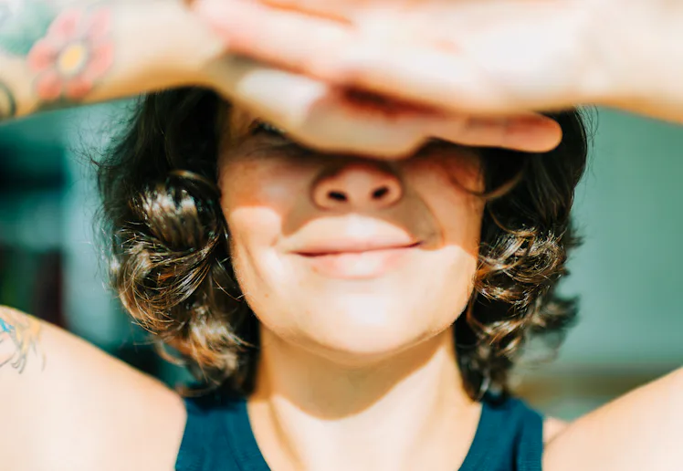 Woman shielding eyes from sun feeling happy