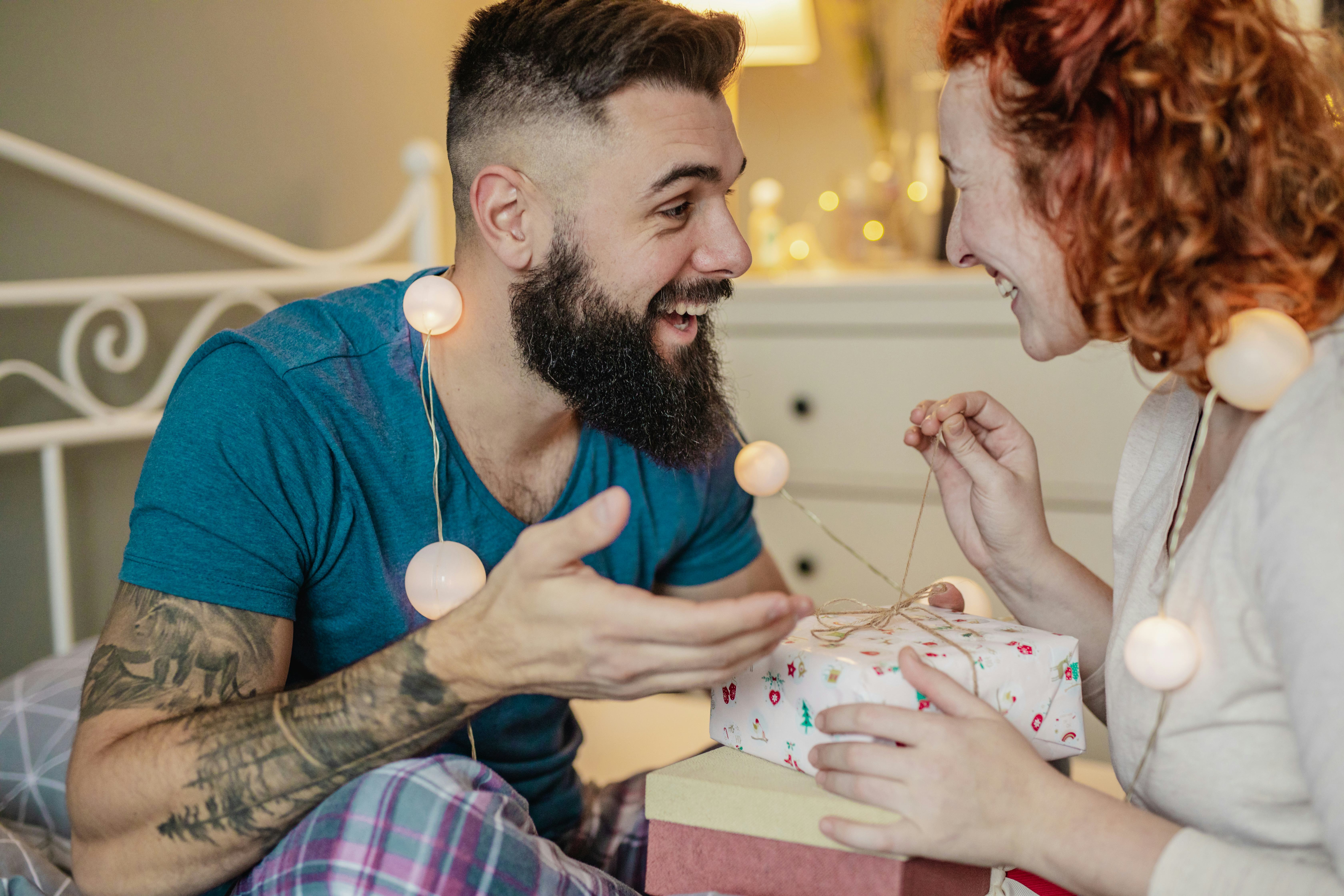 A young couple in the bedroom, man is giving a gift to a woman