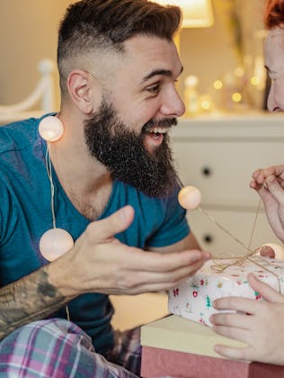 A young couple in the bedroom, man is giving a gift to a woman