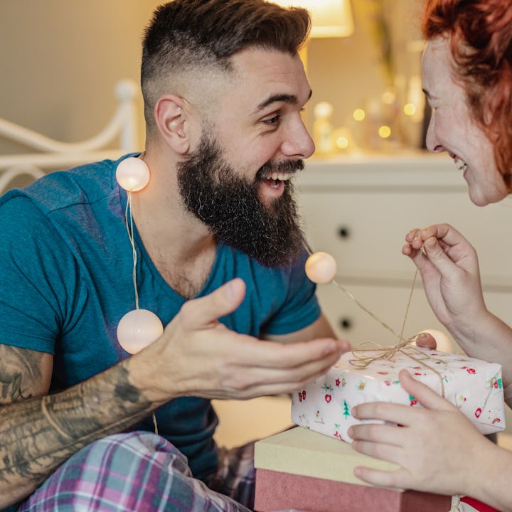 A young couple in the bedroom, man is giving a gift to a woman