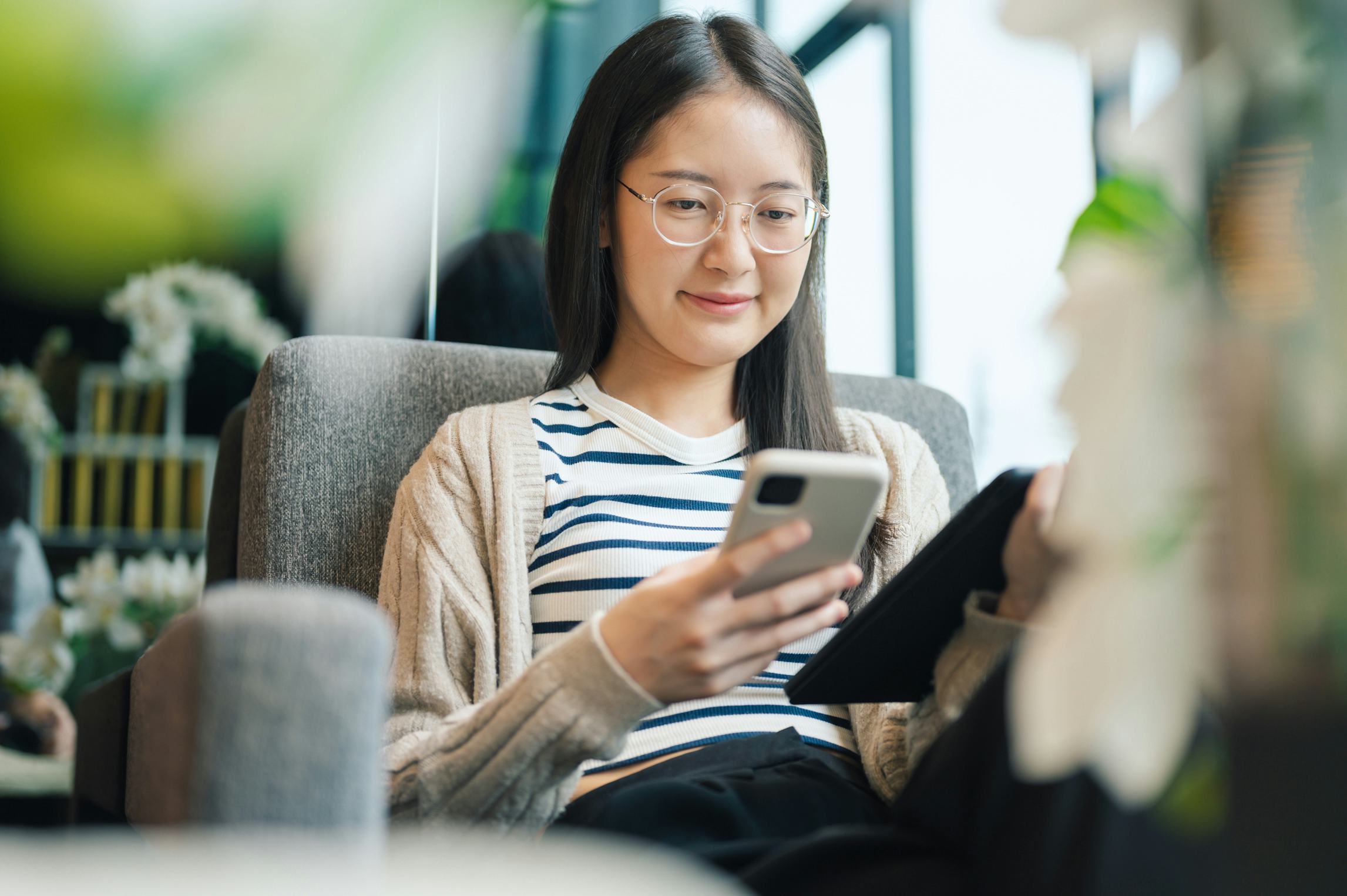 Closeup of a gen zwoman’s hand using a smartphone highlights the tactile connection between people a...