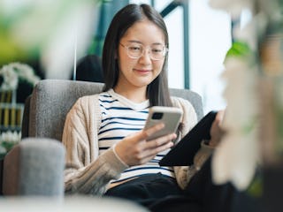 Closeup of a gen zwoman’s hand using a smartphone highlights the tactile connection between people a...
