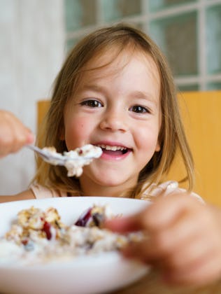 A little girl eats a bowl of oatmeal.