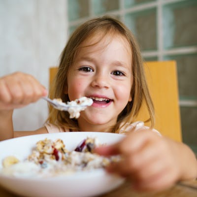 A little girl eats a bowl of oatmeal.