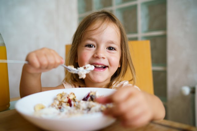 A little girl eats a bowl of oatmeal.