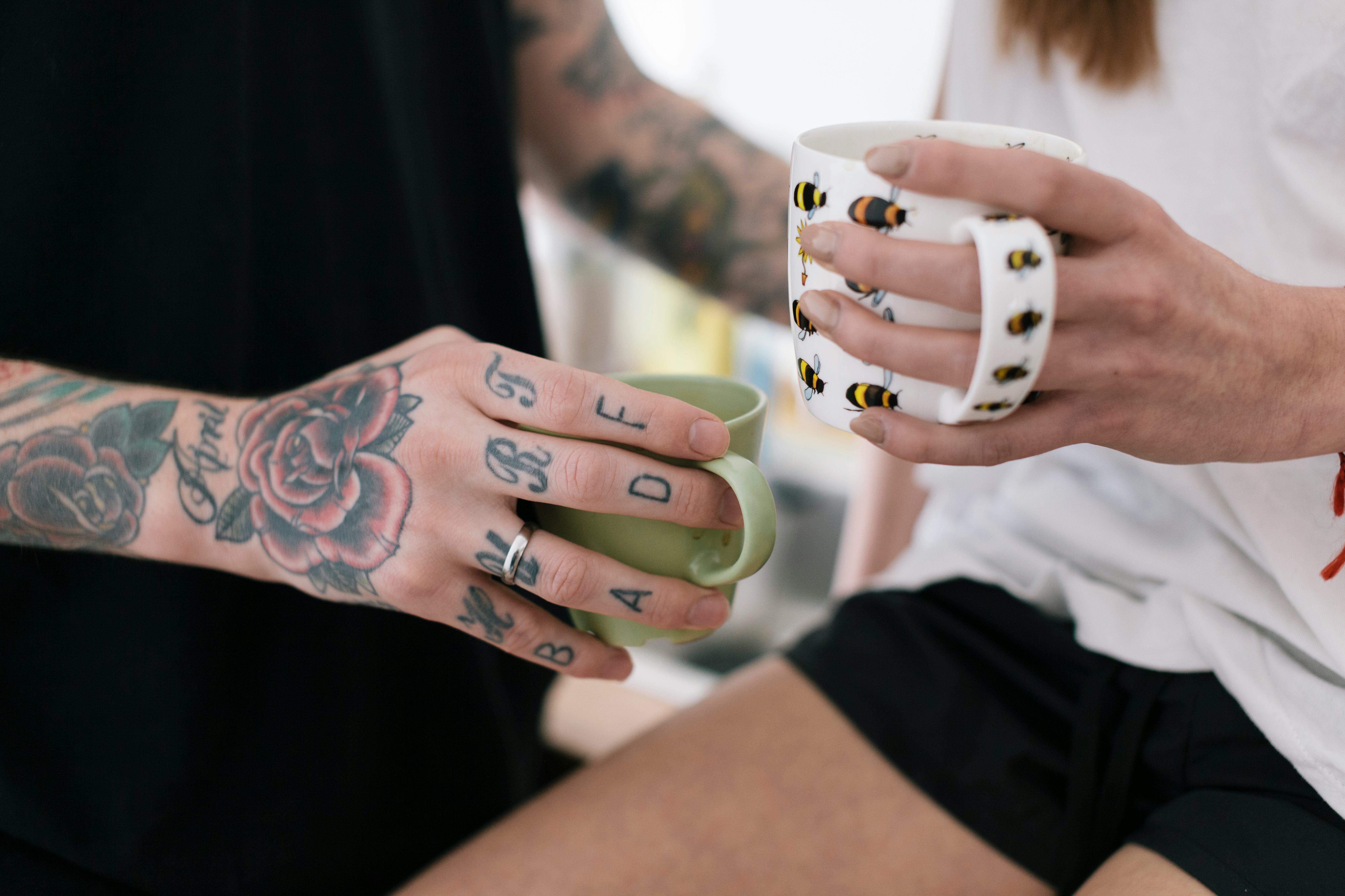 Young couple standing in kitchen having a romantic moment. Man has Tattoos on his hands.