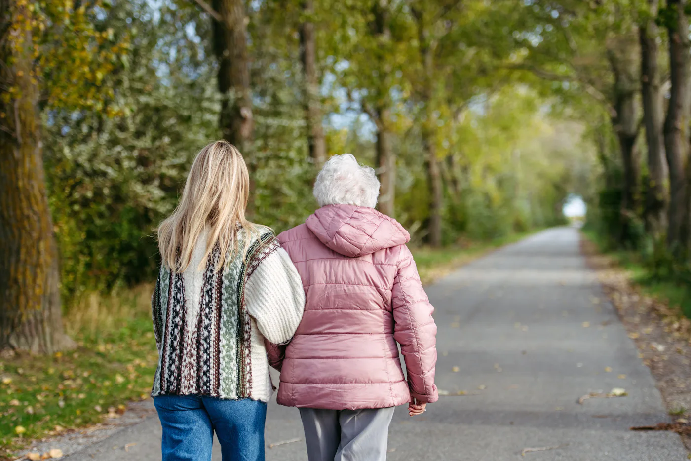 Autumn walk, rear view of senior woman and her daughter spending a chilly, windy day outdoors in nature.