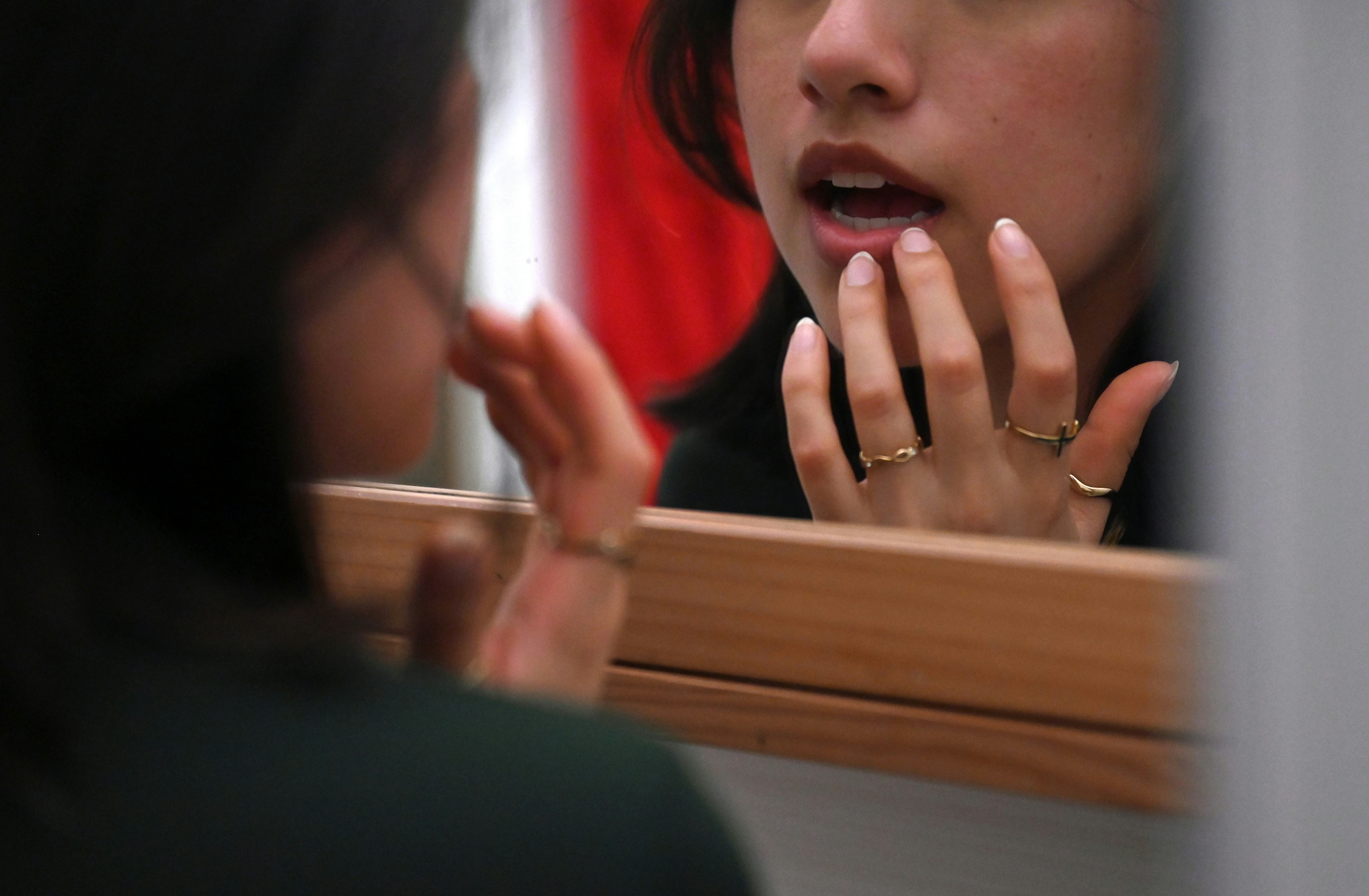 SYMBOL - 02 January 2026, Berlin: A young woman looks at her face in a bathroom mirror. Photo: Elisa...