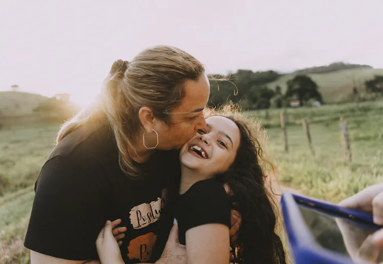 Mother hugging daughter on farm
