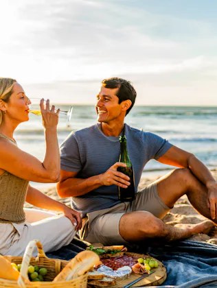 Couple talking and drinking wine during picnic on the beach